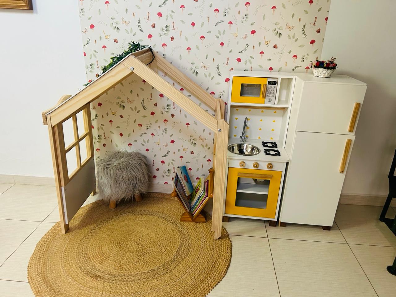 Cantinho da leitura com casinha de madeira e cozinha de brinquedo