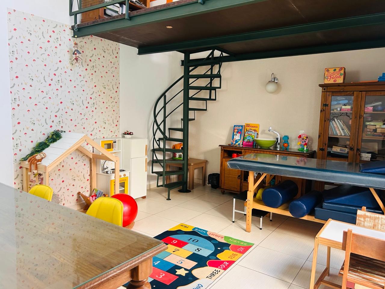 Sala lúdica da Clínica CITI com brinquedos, tapete educativo e maca